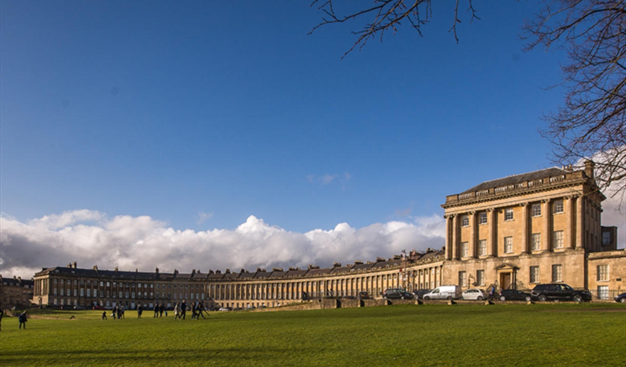 The Royal Crescent in Bath, a curve of Georgian stone houses above a green lawn.