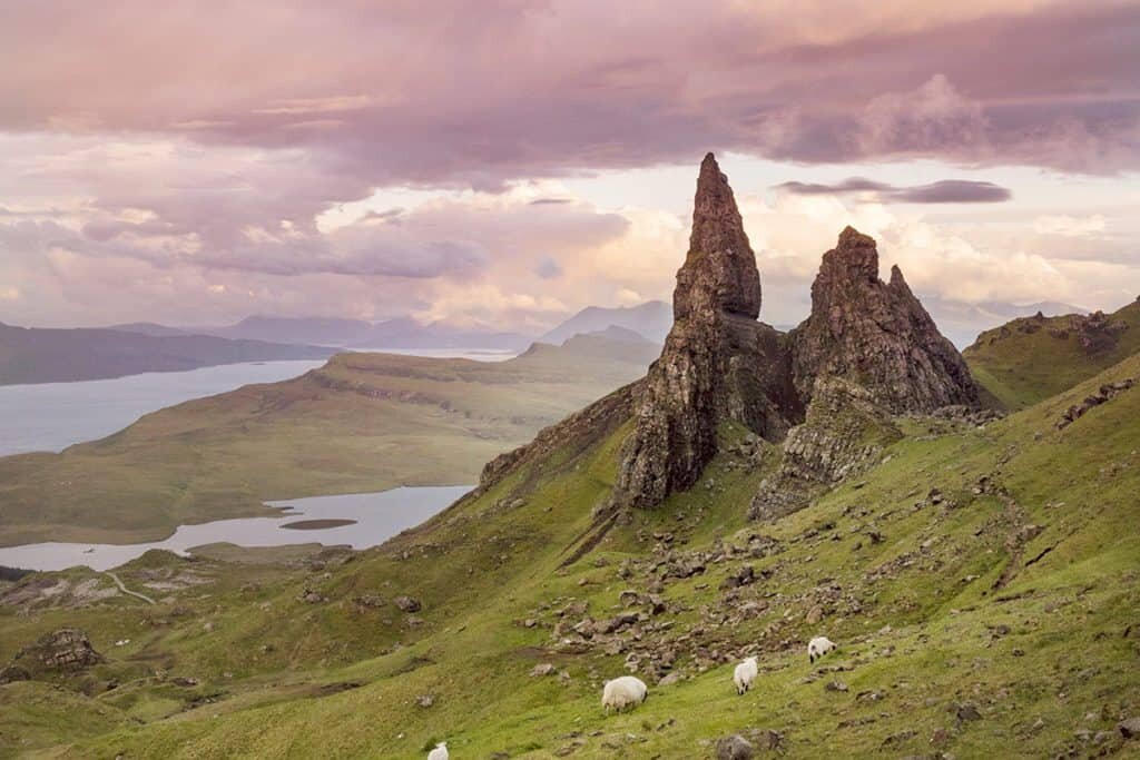 The Old Man of Storr on the Isle of Skye, with sheep on the green slope below.